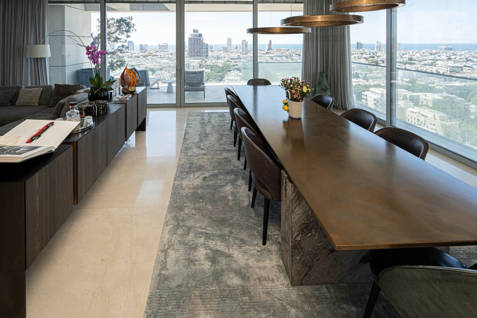 Bronze dining table for twelve beside full-height glazing