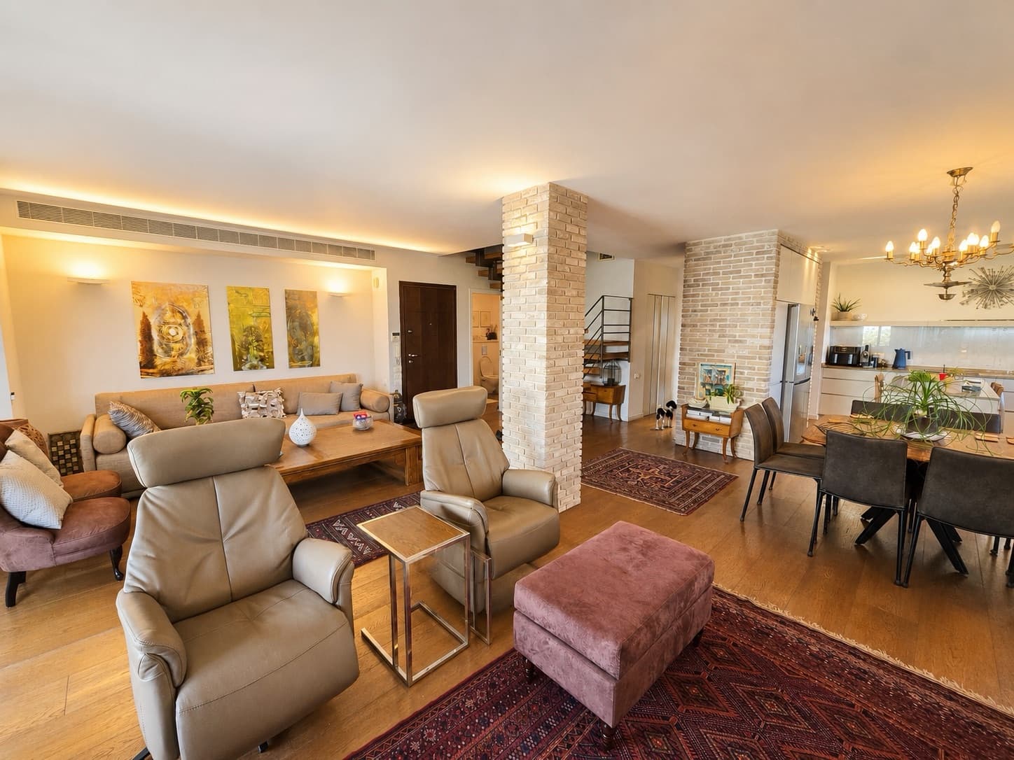 Main living space with exposed brick columns, dining for eight and open-plan kitchen beyond